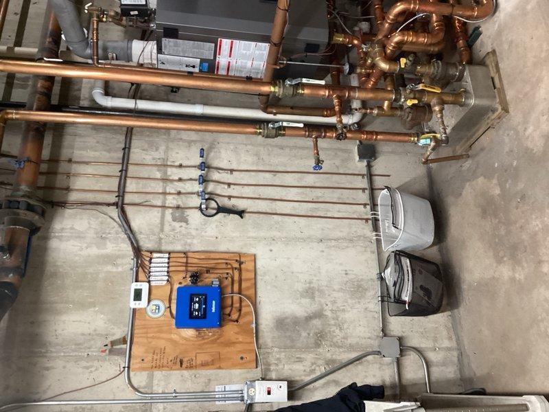 Responded to callback for no heat condition in commercial building with heating system failing to activate below 50°F setpoint despite two previous service visits. Inspected boiler system, copper supply and return piping, zone valves, and thermostat controls mounted on mechanical room wall. Verified temperature gauge readings on main distribution lines and checked all blue-handled isolation valves for proper operation. System diagnostics performed to identify root cause of heating failure and determine necessary corrective action for reliable operation.