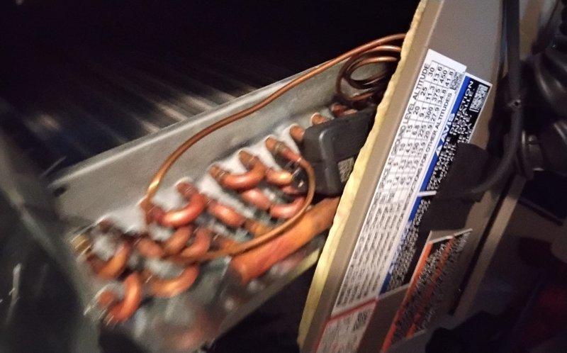 # HVAC Tune-Up Completed

Performed preventive maintenance tune-up on single-system air conditioning unit and air handler. Upon inspection, discovered evaporator coil heavily frosted with ice buildup, particularly concentrated on one side, indicating potential airflow restriction or refrigerant charge issue. Documented equipment condition with photographs showing serpentine copper coil assembly with significant frost accumulation obscuring tubing, beige metal casing with manufacturer specification label, and internal components including blower motor assembly with multi-colored wiring connections. Inspected rooftop unit interior revealing cylindrical blower motor/capacitor mounted on metal plate with proper wire routing. Examined copper refrigerant lines showing normal operational wear, oxidation on fittings, and black insulation wrapping. Completed standard tune-up procedures on accessible components and documented findings for follow-up evaluation of icing condition.
