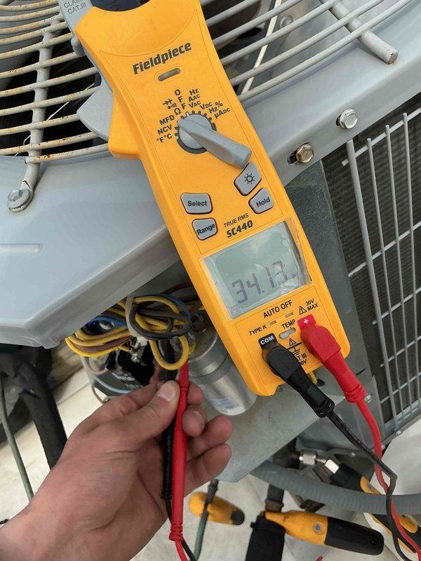Completed commercial air conditioning clean and check per maintenance agreement. Inspected electrical components including dual-run capacitor rated at 35/5μF/440VAC, verified proper operation and connections, and performed diagnostic testing with readings showing system operating within normal parameters at 34.12 on electrical meter.