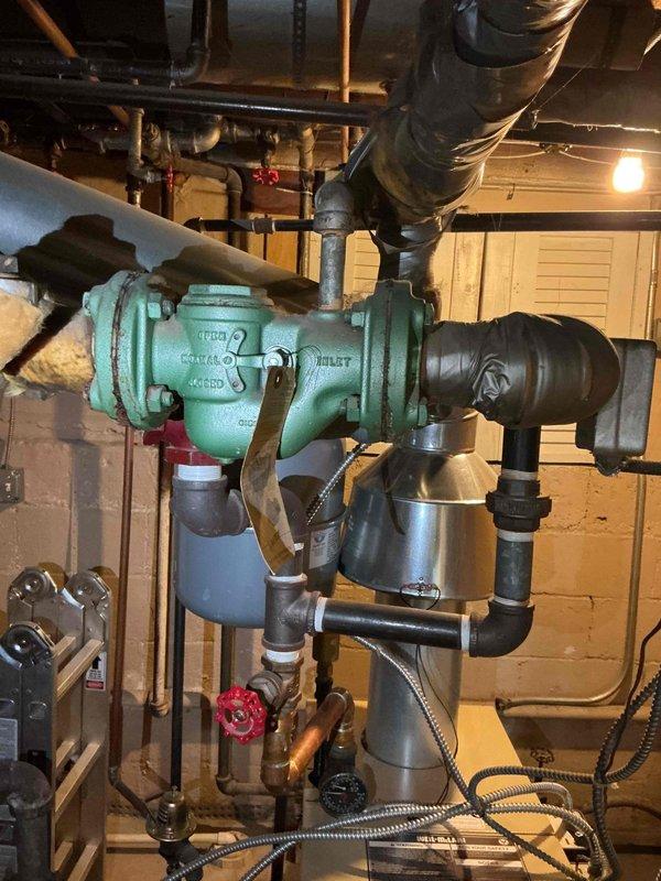 Responded to service call for leaking boiler pipes. Upon inspection, identified active leak at circulator pump connections in basement mechanical room. Observed aged turquoise circulator pump with visible wear on housing and fittings. Examined piping connections, flexible couplings, and valve assemblies surrounding the pump unit. Documented existing conditions with photographs showing pump assembly, copper piping, control valves, and associated plumbing infrastructure. Service provided under platinum plan membership at no charge. Discussed comfort plan options and verified all equipment information was recorded for service records.