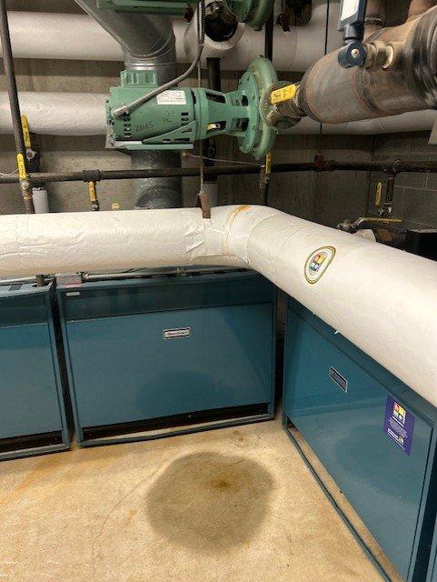 Responded to water leak in commercial boiler room. Upon inspection, identified significant corrosion and rust staining around copper pipe penetration through wall, indicating active leak at pipe junction. Documented conditions with photographs showing water damage on floor near HVAC equipment including air handling units and circulation pumps. Unable to complete repair onsite; provided quote for corrective action to address pipe leak and corrosion damage.