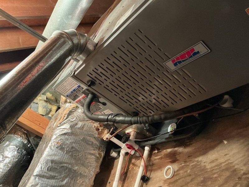 Responded to no cooling complaint on 9-month-old residential AC system. Upon arrival, found Honeywell ProSeries thermostat displaying 69°F setpoint with actual temperature reading of 63.5°F, indicating system was calling for cooling but not achieving desired temperature. Inspected attic-mounted air handler and associated components including refrigerant lines, flexible ductwork, and electrical connections. Diagnosed issue and performed necessary repairs to restore proper cooling operation. System tested and verified operational before departure.