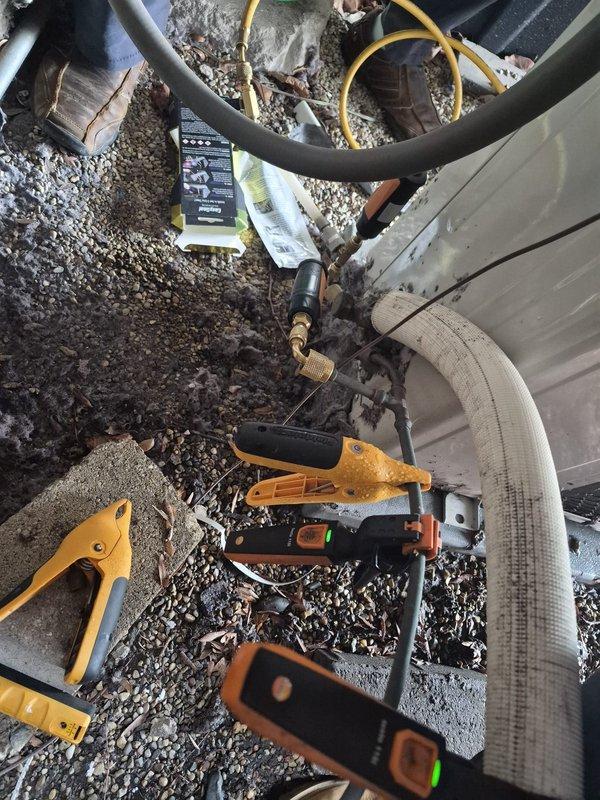 Responded to service call for non-functioning thermostat affecting air conditioning system operation. Upon arrival, performed comprehensive diagnostic evaluation of HVAC system including outdoor condensing unit inspection. Found significant debris accumulation on condenser coil fins restricting airflow, which was contributing to system performance issues. Utilized vacuum pump, refrigerant gauges, and digital diagnostic meters to assess system pressures and operation. Documented equipment condition with photographic evidence showing dirty condenser coil through protective grille and service equipment setup. Verified thermostat communication with system and documented all equipment information for service records.