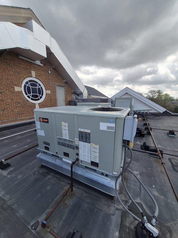 Responded to service call for two rooftop units not cooling at commercial property. Performed visual inspection and diagnostic assessment of both Trane RTU systems mounted on flat membrane roof. Documented equipment condition and identified cooling deficiencies requiring approval process before proceeding with repairs.