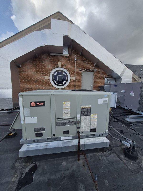Responded to service call for two rooftop units not cooling at commercial property. Performed visual inspection and diagnostic assessment of both Trane RTU systems mounted on flat membrane roof. Documented equipment condition and identified cooling deficiencies requiring approval process before proceeding with repairs.