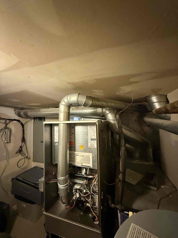 Responded to service call for non-operational air conditioning system and venting issue flagged by inspector for potential carbon monoxide concerns prior to property sale. Performed comprehensive diagnostic assessment of HVAC system including furnace venting configuration, ductwork integrity, and air conditioning components. Inspected furnace installation, exhaust venting pathways, and duct connections throughout basement utility area; documented system configuration and equipment specifications. Evaluated flexible ductwork routing and metallic vent piping for proper installation, clearances, and code compliance. Identified deficiencies requiring correction and provided findings with replacement recommendations to facilitate safe system operation and successful property transfer.