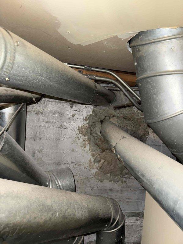 Responded to service call for non-operational air conditioning system and venting issue flagged by inspector for potential carbon monoxide concerns prior to property sale. Performed comprehensive diagnostic assessment of HVAC system including furnace venting configuration, ductwork integrity, and air conditioning components. Inspected furnace installation, exhaust venting pathways, and duct connections throughout basement utility area; documented system configuration and equipment specifications. Evaluated flexible ductwork routing and metallic vent piping for proper installation, clearances, and code compliance. Identified deficiencies requiring correction and provided findings with replacement recommendations to facilitate safe system operation and successful property transfer.