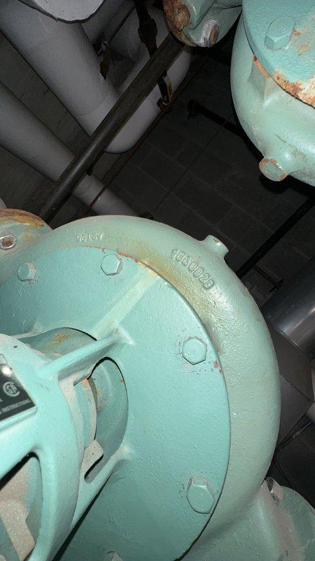 Responded to service request to document bearing condition on HVAC equipment unit 1304-028. Photographed turquoise-painted mechanical housing showing visible wear, rust staining at seams and joints, and associated piping system with insulated sections for maintenance records and assessment purposes.