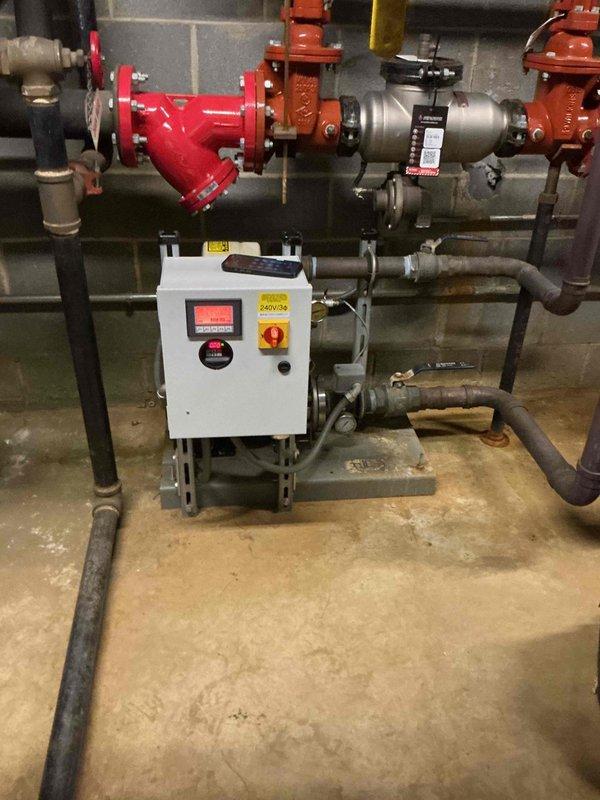 Continued diagnostic evaluation of commercial boiler booster pump system experiencing low pressure alarm condition. Inspected control panel interface, pressure monitoring display reading 0.00, and associated pump assembly with piping network including isolation valves and Y-strainer. Coordinated with office to establish approval process through property management for additional repairs required to resolve system malfunction.