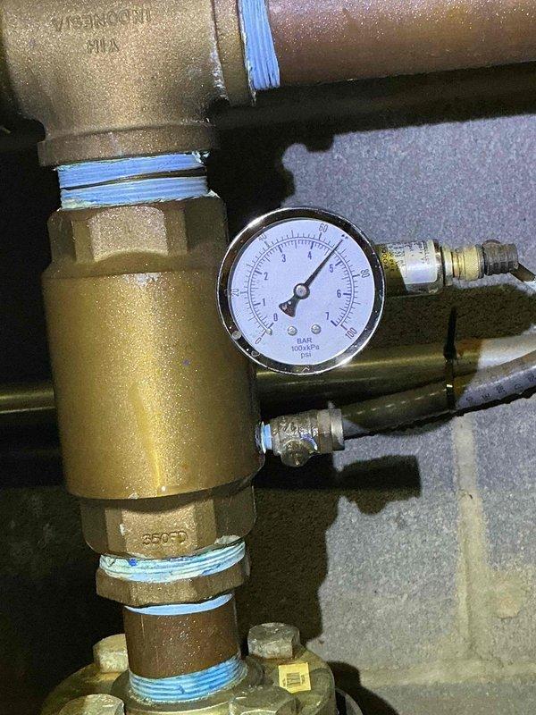 Installed pressure monitoring system on booster pump assembly by adding tee fitting with gauge on 2" inlet side. Replaced defective pressure gauge at booster pump location and installed new gauge near expansion tank downstream. Addressed water leak concerns in mechanical room where evidence of moisture and water staining was present on concrete floor beneath copper piping system with oxidized connections and multiple ball valves.