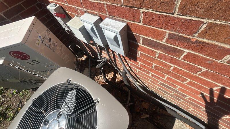 Performed seasonal air conditioning start-up service and diagnosed condenser noise issue on residential outdoor unit. Inspected condenser unit, electrical disconnect, and associated components mounted on exterior wall. Discussed service contract renewal options covering multiple HVAC systems including air conditioners, mini-split, and furnaces, with maintenance scheduling recommended for upcoming month.