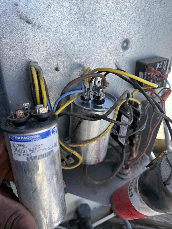 Replaced two failed capacitors in HVAC unit that were previously diagnosed during prior service visit. Removed old capacitors and installed new TITAN PRO 370 VAC replacement capacitors, ensuring proper electrical connections and secure mounting of all components.