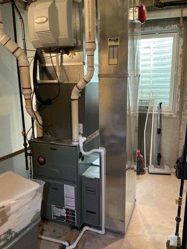 Responded to service call for humidifier leakage issue in basement mechanical room. Inspected wall-mounted beige humidifier unit connected to gray furnace system via flexible ductwork. Assessed HVAC equipment including furnace, air handler, and associated plumbing connections for signs of water leakage or moisture damage. Evaluated heavily soiled air filter showing significant dirt accumulation and discoloration, indicating compromised air quality and reduced system efficiency. Documented equipment conditions through photography for maintenance records. Provided estimate for comprehensive maintenance plan covering multiple HVAC components including air conditioning units, furnaces, humidifiers, and water heaters, with installation scheduled pending approval.