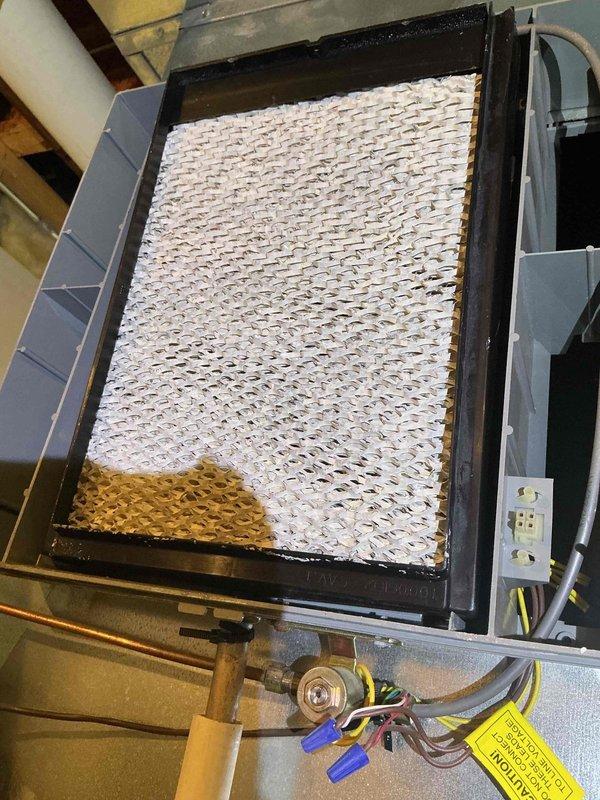 Responded to service call for humidifier leakage issue in basement mechanical room. Inspected wall-mounted beige humidifier unit connected to gray furnace system via flexible ductwork. Assessed HVAC equipment including furnace, air handler, and associated plumbing connections for signs of water leakage or moisture damage. Evaluated heavily soiled air filter showing significant dirt accumulation and discoloration, indicating compromised air quality and reduced system efficiency. Documented equipment conditions through photography for maintenance records. Provided estimate for comprehensive maintenance plan covering multiple HVAC components including air conditioning units, furnaces, humidifiers, and water heaters, with installation scheduled pending approval.