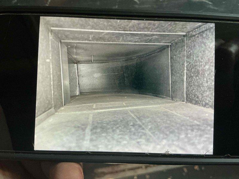 Completed comprehensive duct cleaning service for single-system HVAC installation in condominium unit. Accessed and cleaned rectangular metal ductwork, removing accumulated dust and debris from interior surfaces. Documented pre-service conditions showing dust accumulation and discoloration within galvanized steel ducts, then performed thorough cleaning of accessible duct runs and main trunk lines. Verified proper access through wall-mounted register openings and ensured all components were properly reassembled upon completion.