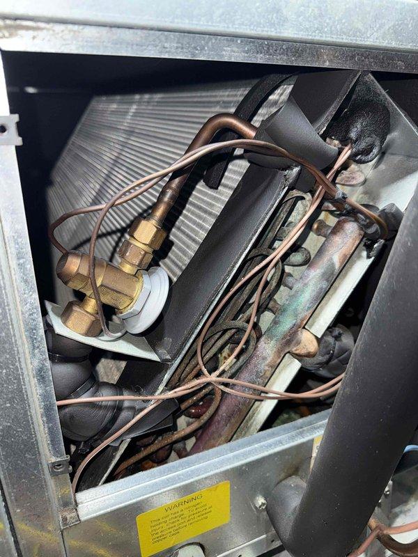 Completed spring maintenance clean and check on air conditioning and air handler combination system per comfort plan guidelines. Performed thorough inspection of refrigerant lines, heat exchanger coil, and electrical connections within the unit compartment, noting normal patina development on copper components. Recorded supply air temperature reading of 79.4°F using digital measurement equipment to verify proper system operation and airflow performance.