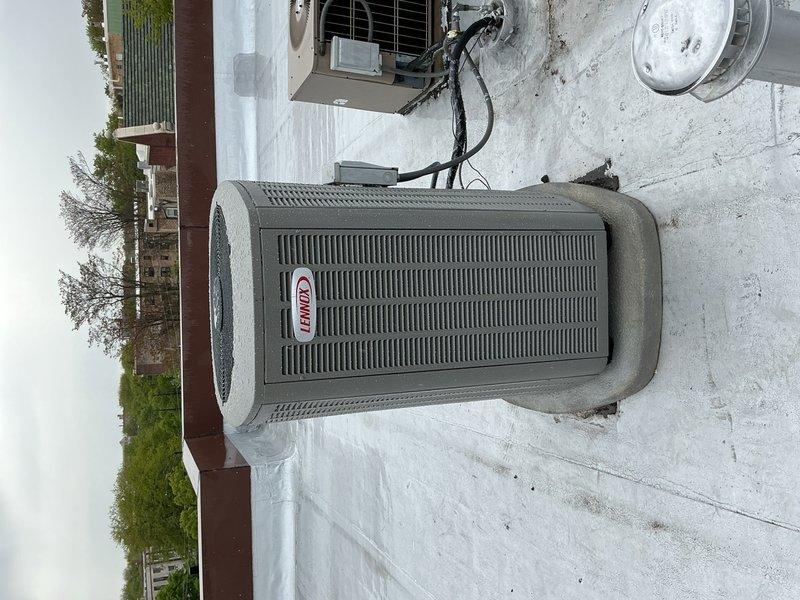 Completed full HVAC system replacement including outdoor Lennox condensing unit and indoor evaporator coil. Unit was carefully transported to installation location and positioned on existing concrete pad with proper electrical conduit connections from building exterior. Installed new control module with integrated relay system inside air handler cabinet, verified all wiring connections, and confirmed green LED indicator showing proper power supply to system controls.
