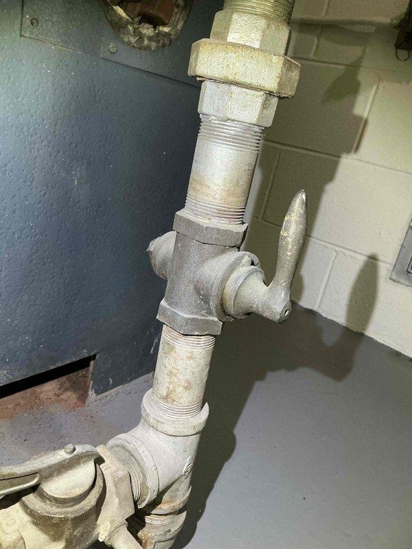 Responded to emergency service call where gas utility had shut off gas supply to commercial building boiler due to detected gas leak. Upon arrival, inspected boiler system and associated gas piping infrastructure, including galvanized steel pipe connections, unions, and fittings throughout the mechanical room. Identified leak source in aged galvanized gas piping system showing significant weathering and deterioration. Documented existing conditions with photos of affected piping assembly and boiler equipment. Coordinated with office to obtain necessary approvals from property management prior to proceeding with repairs. System remained shut down pending authorization and scheduling of leak repair work to restore safe operation of building heating system.