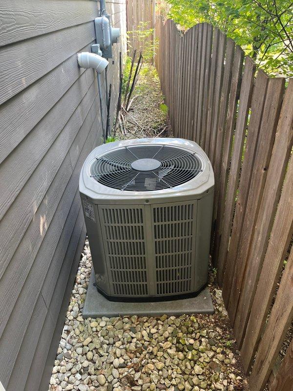 Completed HVAC system replacement including furnace and air conditioning unit installation. The outdoor condenser unit was positioned on a concrete pad in the side yard with proper clearances maintained between the house and fence line. Refrigerant lines and electrical connections were routed along the exterior wall using appropriate conduit and PVC piping. The compressor component was sourced and installed as part of the AC replacement to restore full system functionality.