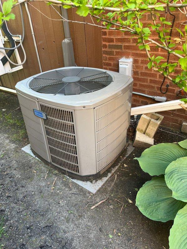 Completed air conditioning replacement estimate for 11-year-old residential cooling system that had required refrigerant recharge the previous year. Evaluated existing outdoor condenser unit positioned on concrete pad against brick wall with electrical disconnect and condensate drainage in place. Discussed replacement options for aging AC system while noting that existing 3-year-old furnace remains serviceable, and addressed customer's ongoing concern regarding intermittent furnace noise that occurs when air conditioning operates, recommending further diagnostic evaluation if issue persists after AC replacement.