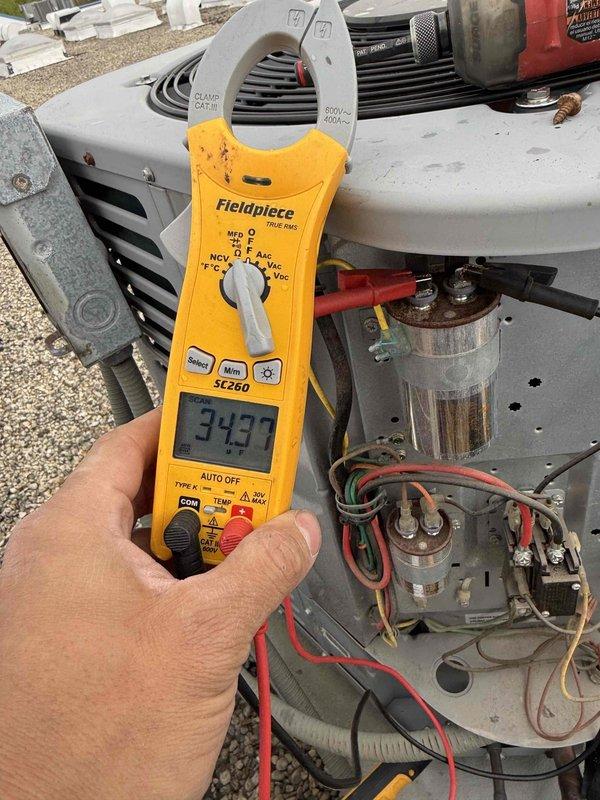 Responded to reported water leak at furnace filter area in condo unit. Upon inspection, accessed HVAC system and performed diagnostic testing of electrical components using clamp meter, which displayed a reading of 343 on the Fieldpiece SC260 instrument. Examined internal components including capacitor, wiring connections, and mounting hardware to identify source of moisture intrusion. Verified proper operation of blower motor assembly and inspected mounting plate for potential condensation issues related to the reported leak.