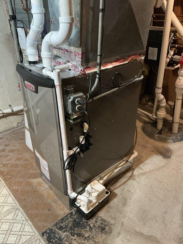 Removed and properly disposed of existing forced air furnace from basement installation. Installed new Lennox SLP99UH070XV36BK 66,000 BTU 3-stage variable speed forced air furnace (Cat #26J92) with furnace raised off ground using vibration pads to reduce operational noise and vibration transfer. 

Fabricated and installed necessary sheet metal transitions to connect new unit to existing supply and return air ductwork, with adjustments made to return air drop for proper airflow. Connected unit to existing gas line with appropriate fittings and valves, verified gas pressure and connections for safety compliance. Attached to existing electrical circuit with proper junction box installation and wiring connections.

Installed new condensate pump to handle drainage from high-efficiency furnace operation. Connected and properly pitched all PVC vent piping with support brackets installed every 4 feet as required by manufacturer specifications and code requirements. Secured exhaust venting to e
