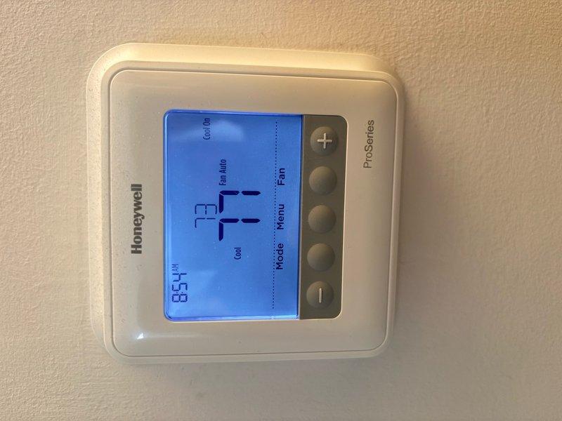 Completed air conditioning tune-up and maintenance inspection on single system. Verified thermostat operation with display reading 74°F and confirmed proper cooling mode functionality. Performed electrical diagnostics using clamp meter, measuring amperage draw at 9.96 amps on outdoor unit compressor circuit, indicating normal operating parameters within manufacturer specifications.