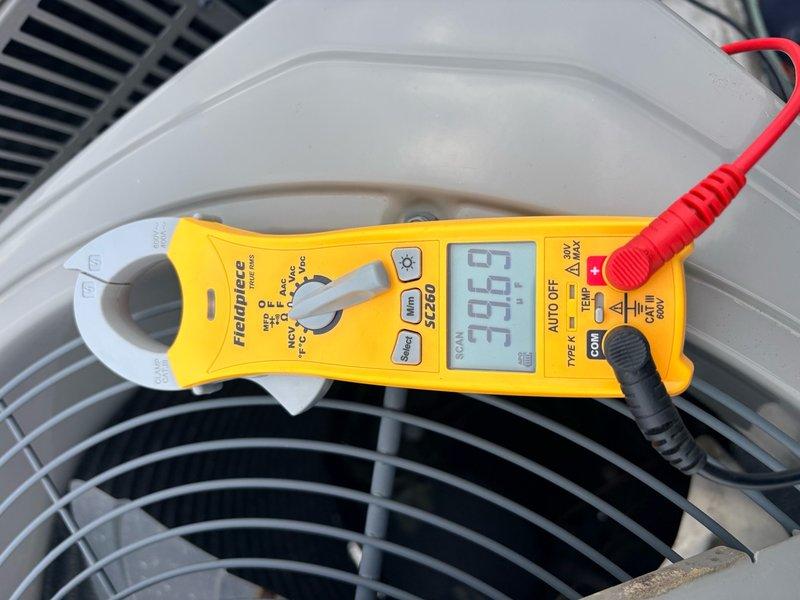 Completed air conditioning tune-up and maintenance inspection on single system. Verified thermostat operation with display reading 74°F and confirmed proper cooling mode functionality. Performed electrical diagnostics using clamp meter, measuring amperage draw at 9.96 amps on outdoor unit compressor circuit, indicating normal operating parameters within manufacturer specifications.