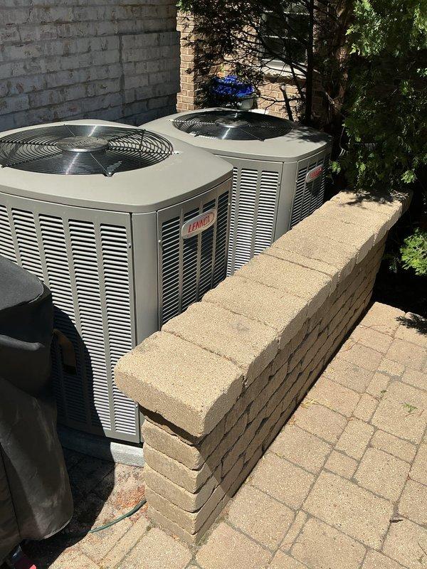 Completed warranty repositioning of two Lennox condenser units on concrete block pad. Rotated unit nearest access door to match orientation of adjacent unit and relocated both condensers to the right side of pad to optimize placement. Verified proper clearances and confirmed units remained level and secure on mounting surface following adjustment.
