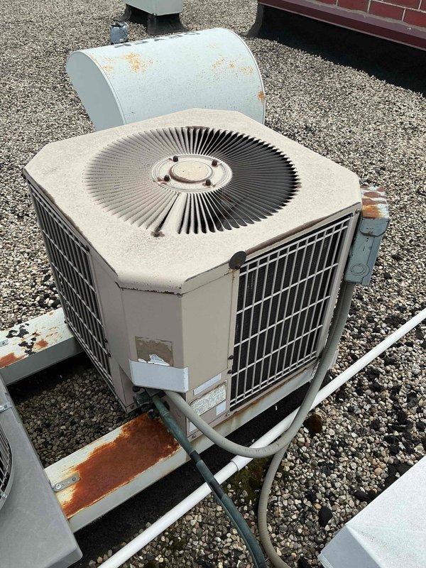 Responded to no cooling complaint on rooftop-mounted air conditioning unit of undetermined age, estimated at 10+ years old. Upon arrival, found system completely inoperative with thermostat also shut down. Conducted visual inspection revealing aged condenser unit with significant rust deterioration on mounting platform, housing panels, and associated components. Extensive corrosion noted around equipment base and mounting hardware, indicating prolonged exposure to weather elements. Unit exhibited signs of advanced age including surface weathering, dust accumulation, and oxidation throughout. Performed diagnostic evaluation to determine extent of system failure and assessed overall equipment condition. Due to age of equipment, advanced deterioration, and complete system shutdown, recommended full system replacement as most cost-effective solution versus attempting repairs on aging unit with compromised structural integrity.