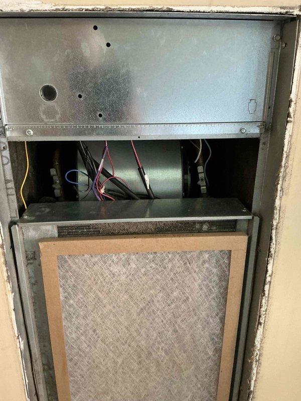 Responded to service call for 1.5 ton through-the-wall heat pump unit scheduled for replacement. Added refrigerant to existing system as temporary measure until new equipment installation. Documented interior components including blower motor assembly, wiring connections, and filter condition, as well as exterior grille and performed diagnostic measurements using digital meter.