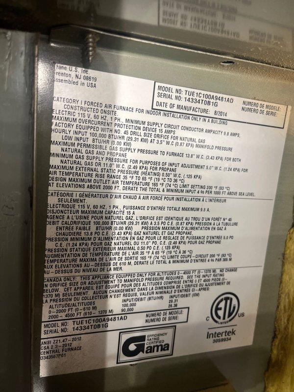 Completed preventative maintenance clean and check service on residential forced air furnace and air conditioning system per maintenance agreement guidelines. Inspected Trane TUE1C100A9481AD furnace unit manufactured August 2014, verified all technical specifications and safety certifications on equipment nameplate, and documented electrical panel configuration with circuit breaker arrangement and main disconnect switch for system reference.