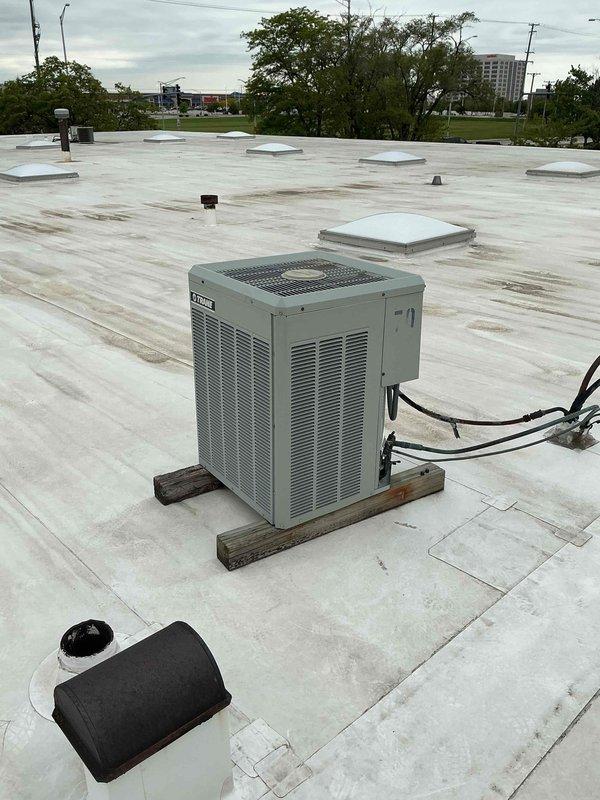 Replaced 3-ton rooftop air conditioning unit serving the rear office area of commercial building. Unit was installed on wooden support blocks with proper elevation above roof membrane, and electrical conduit was routed and connected to power source.