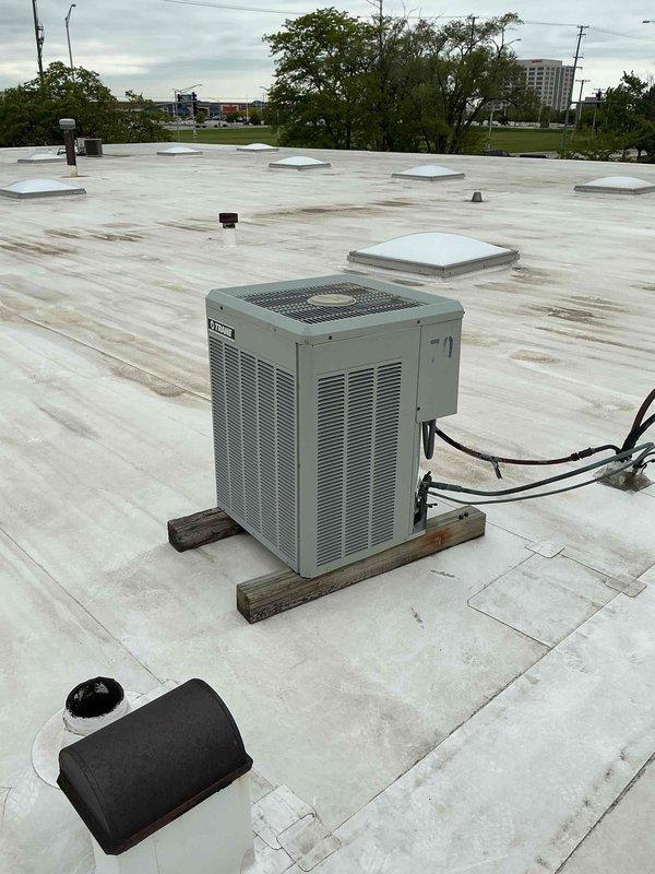 Replaced 3-ton rooftop air conditioning unit serving the rear office area of commercial building. Unit was installed on wooden support blocks with proper elevation above roof membrane, and electrical conduit was routed and connected to power source.