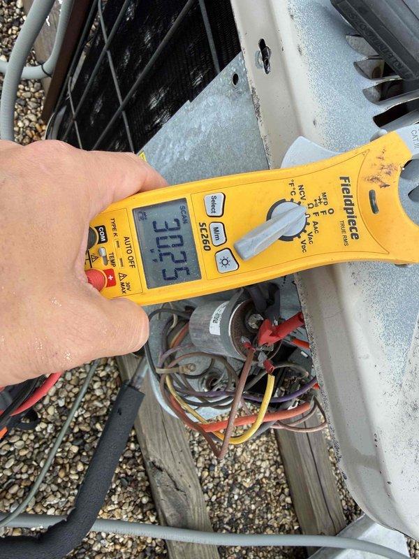 Responded to no cooling complaint on rooftop air conditioning unit serving condo apartment. Upon arrival, performed electrical diagnostics using digital multimeter to test voltage and amperage at outdoor condenser unit. Measurements taken at junction box revealed voltage reading of 30.55V and current draw of 15A during testing. Inspected electrical connections, wiring harness, and capacitor/contactor assembly with access panel removed to diagnose cooling failure.