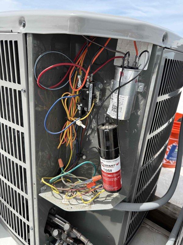 Responded to no cooling complaint on rooftop air conditioning unit that had been running continuously for 45 minutes without achieving setpoint of 72°F. Upon inspection, found outdoor condenser unit operational but system failing to cool effectively. Accessed internal electrical compartment and discovered failed dual run capacitor preventing proper compressor and condenser fan operation. Replaced defective capacitor with manufacturer-specified component, verified proper electrical connections, and tested system operation. Unit cycled properly and began producing cold air at supply registers. Documented equipment information and captured photos of outdoor unit and internal electrical components for service records.