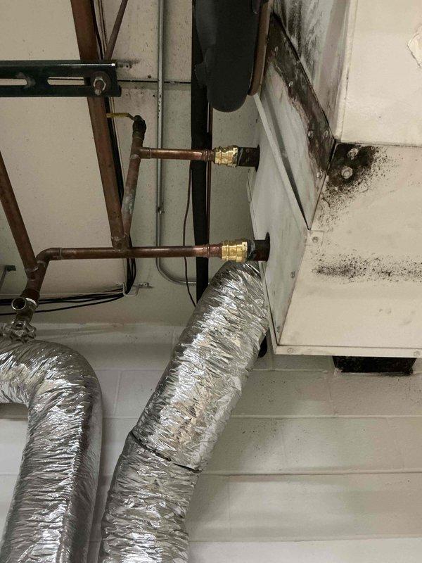Responded to commercial facility for reported leak at lobby air handler system. Upon inspection, identified active leak at corroded galvanized steel union fittings connecting copper refrigerant lines. Evidence of significant water damage and mold growth on surrounding wall surfaces indicated leak had been present for extended period. Replaced failed union fittings with new brass compression fittings to restore system integrity. Tested all connections for proper seal and verified no additional leaks present. System returned to normal operation. Documented conditions with photos showing before state of corroded fittings and water damage for facility records.