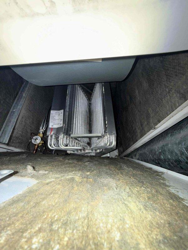 Completed air handler and air conditioning clean and check per building special maintenance agreement. Performed visual inspection of evaporator coil assembly and refrigerant line connections, verified system components accessible in confined installation space, and conducted electrical diagnostics using digital multimeter to confirm proper system operation. Customer declined filter replacement at time of service.