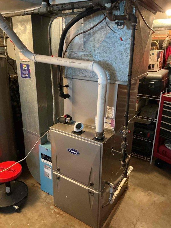 Completed spring maintenance and clean-and-check service on residential Carrier HVAC system per comfort plan agreement. Performed comprehensive inspection of furnace and air conditioning components, verified system operation with digital measurement tools, and documented equipment condition with photos showing proper installation and functionality of all mechanical components in basement utility space.