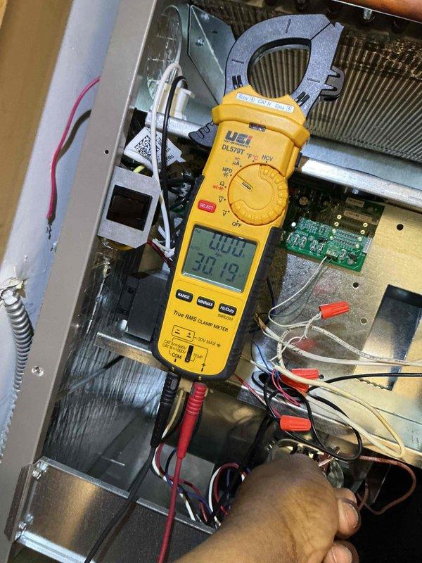 Completed comprehensive tune-up on air conditioning and air handler system. Performed electrical diagnostics using clamp meter to verify proper amperage draw and voltage readings across system components, documenting readings of 333V, 25A, 20.01A, and 30.13V at various test points. Inspected heat exchanger coils, circuit board, and all electrical connections for proper operation. Installed 18x20x1 air filter, entered equipment information into system database, and captured documentation photos of diagnostic procedures and equipment condition.