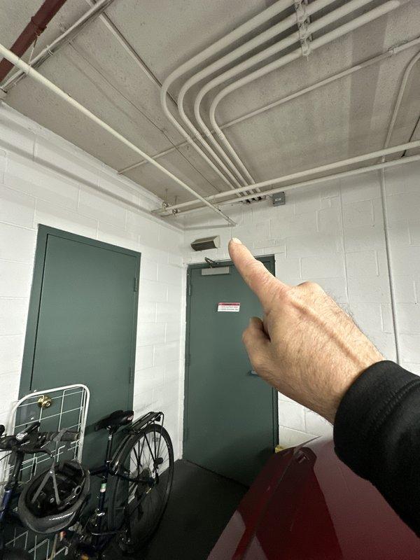 Completed commercial HVAC site visit to inspect ceiling-mounted ductwork and conduit routing in interior corridor and underground parking garage. Documented existing mechanical infrastructure including white-painted conduits, fluorescent lighting fixtures, and exposed ductwork with red and black painted beams for maintenance records and future service reference.
