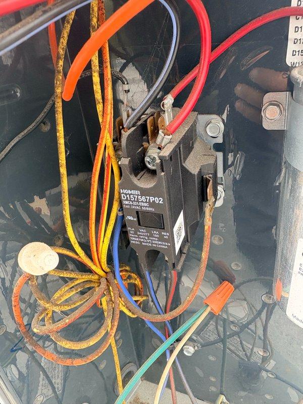 Completed comprehensive tune-up service on a rooftop-mounted cylindrical air conditioning condenser unit. Performed standard maintenance procedures including inspection of electrical components, contactor operation, and refrigerant line connections. Noted deteriorated wire insulation on yellow-striped conductors within the control panel, indicating age-related wear requiring future attention. All system components operational at time of service completion, with photographic documentation captured for service records.
