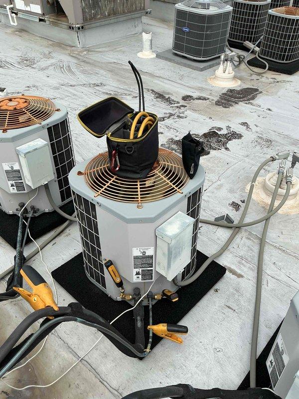 Completed comfort plan clean and check maintenance on 18-year-old Carrier rooftop HVAC system. Performed standard inspection procedures including visual examination of condenser unit, fan assembly, and exterior components. Noted visible corrosion on copper fan guard and typical wear consistent with unit age. Documented system condition with photographs showing rooftop installation layout and equipment status. Based on unit age and manufacturer history, flagged potential heat exchanger concerns for future monitoring, particularly in area behind high limit switch where cracks commonly develop in older Carrier furnaces.