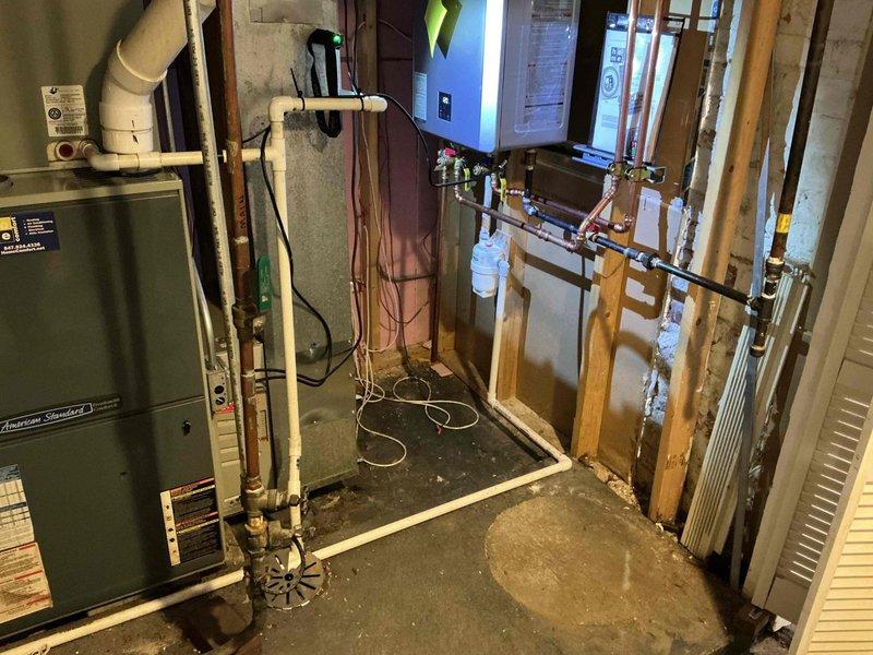 Performed comprehensive clean and check maintenance on American Standard HVAC system, including thorough inspection of air conditioning components and heat exchanger evaluation. Installed bypass recirculating component under furthest sink location and verified operational parameters of recently installed equipment. Conducted diagnostic testing with digital instruments, recording temperature readings and assessing system performance, while documenting condensate drain condition showing mineral deposit accumulation on components.