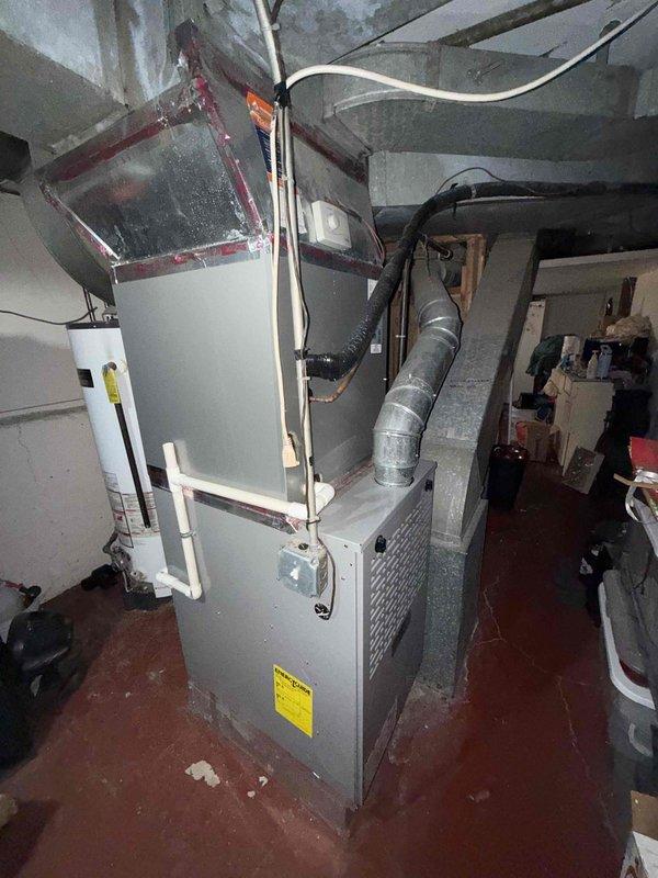 Completed preventative maintenance tune-up on single-zone residential HVAC system located in basement utility area. Performed comprehensive inspection of furnace and air conditioning components, including evaporator coil which showed normal condensation patterns indicating proper operation. Verified condensate drain line functionality with visible water flow through clear tubing and proper drainage through PVC piping system. Inspected all electrical connections, ductwork connections including flexible metallic ducting, and verified proper clearances around equipment. System operating within normal parameters with no deficiencies noted at time of service.