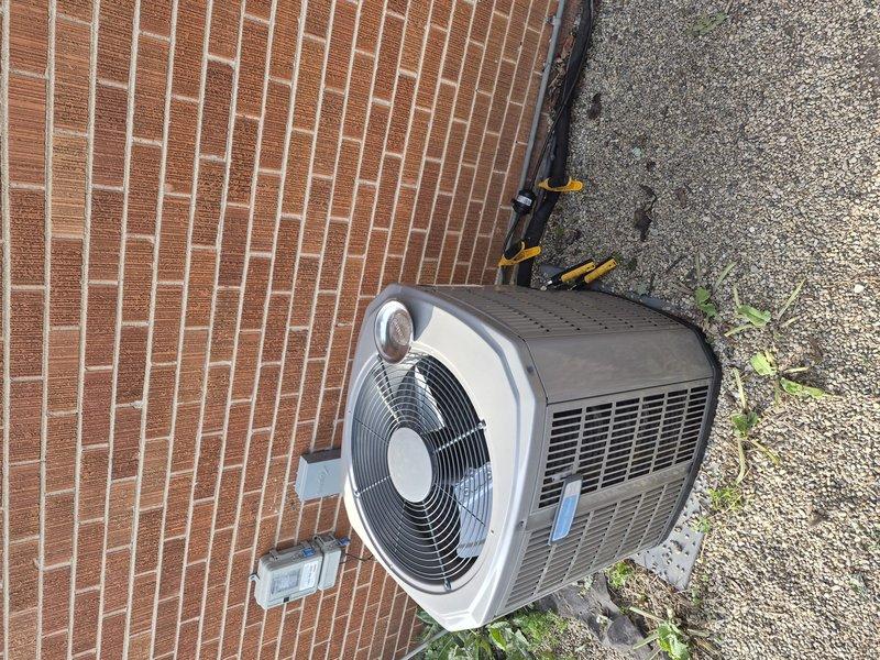 Responded to no cooling call and diagnosed refrigerant leak on outdoor condenser unit. Customer reported similar issue occurred the previous year, indicating potential chronic leak condition. Performed visual inspection of condenser unit positioned against brick exterior wall, checking refrigerant lines, connections, and coil assembly for signs of active leakage. Documented equipment condition with photos showing unit placement and surrounding area. Collected standard dispatch fee and explained diagnostic process, additional labor charges, and available flat rate repair options. Discussed preventative maintenance plan benefits and documented all equipment model and serial number information for service records.