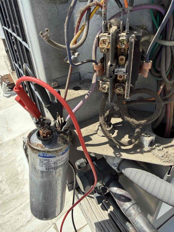 Responded to no cooling complaint at commercial office space. Upon arrival, performed diagnostic testing on outdoor condensing unit. Inspected electrical components including contactor and run capacitor using clamp meter to verify proper operation. Capacitor tested within acceptable microfarad range. Contactor showed heavy dirt and grime accumulation but functionally operational. System powered up and cycled normally with all electrical connections secure. Unit returned to normal cooling operation.