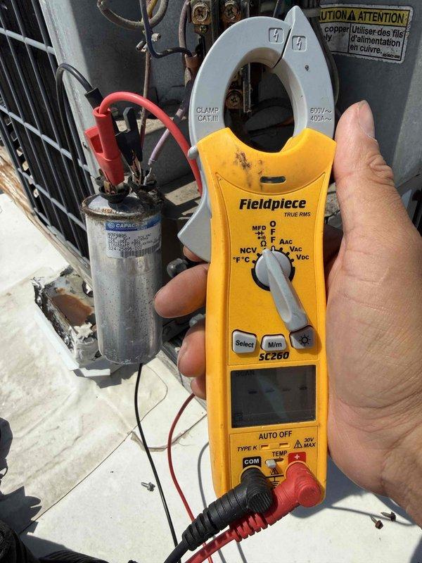 Responded to no cooling complaint at commercial office space. Upon arrival, performed diagnostic testing on outdoor condensing unit. Inspected electrical components including contactor and run capacitor using clamp meter to verify proper operation. Capacitor tested within acceptable microfarad range. Contactor showed heavy dirt and grime accumulation but functionally operational. System powered up and cycled normally with all electrical connections secure. Unit returned to normal cooling operation.