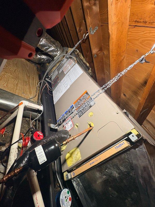 Completed installation of new refrigerant lineset for attic-mounted air handler system. Ran insulated copper refrigerant lines with proper brass fittings and service valves, secured air handler unit with chain suspension from ceiling joists, and connected all ductwork and condensate drainage components. System tested and confirmed operational upon completion with all refrigerant connections properly sealed and insulated.
