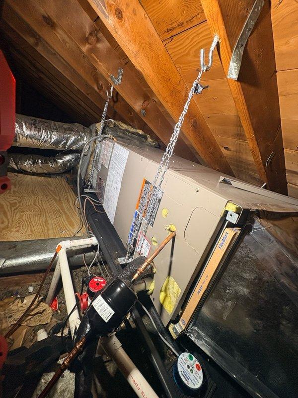 Completed installation of new refrigerant lineset for attic-mounted air handler system. Ran insulated copper refrigerant lines with proper brass fittings and service valves, secured air handler unit with chain suspension from ceiling joists, and connected all ductwork and condensate drainage components. System tested and confirmed operational upon completion with all refrigerant connections properly sealed and insulated.